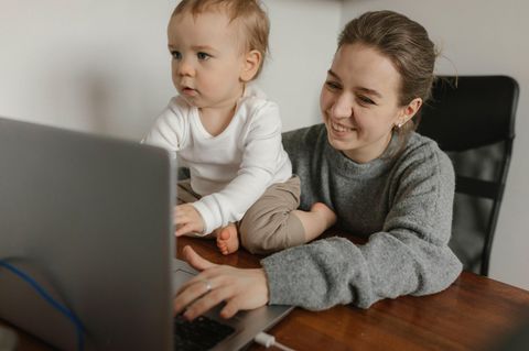 Eine Frau sitzt mit einem kleinen Kind vor einem Laptop