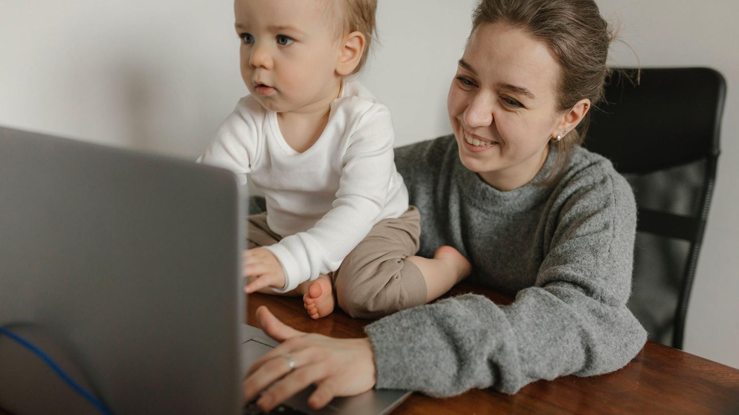 Eine Frau sitzt mit einem kleinen Kind vor einem Laptop