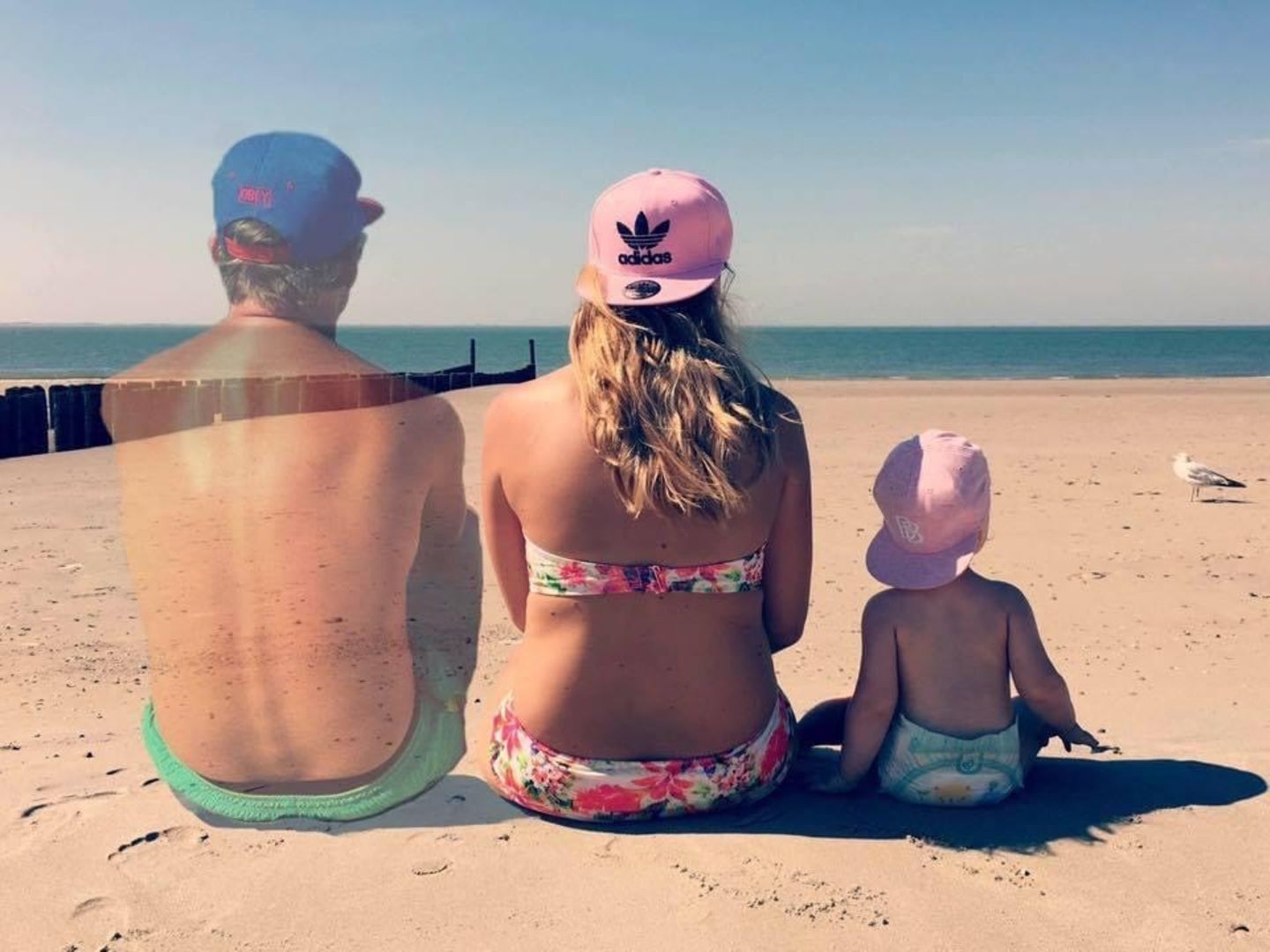 Die Familie sitzt am Strand. Der Mann verpasst langsam.