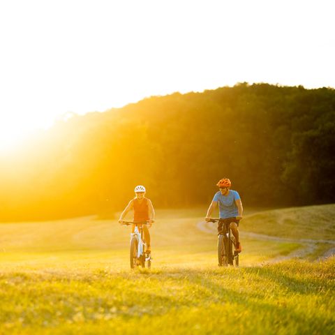 Ein Paar fährt auf E-Bikes über einen Feldweg