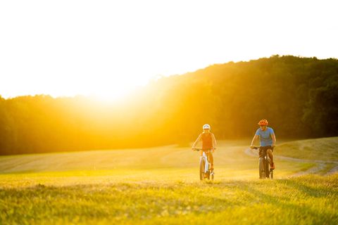 Ein Paar fährt auf E-Bikes über einen Feldweg