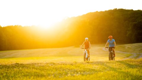 Ein Paar fährt auf E-Bikes über einen Feldweg