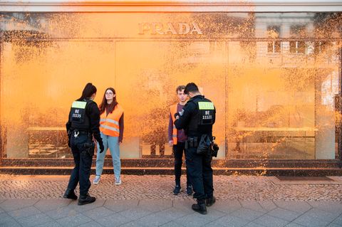 Polizisten kontrollieren Aktivisten vor farbbesprühten Schaufenstern eines Geschäfts