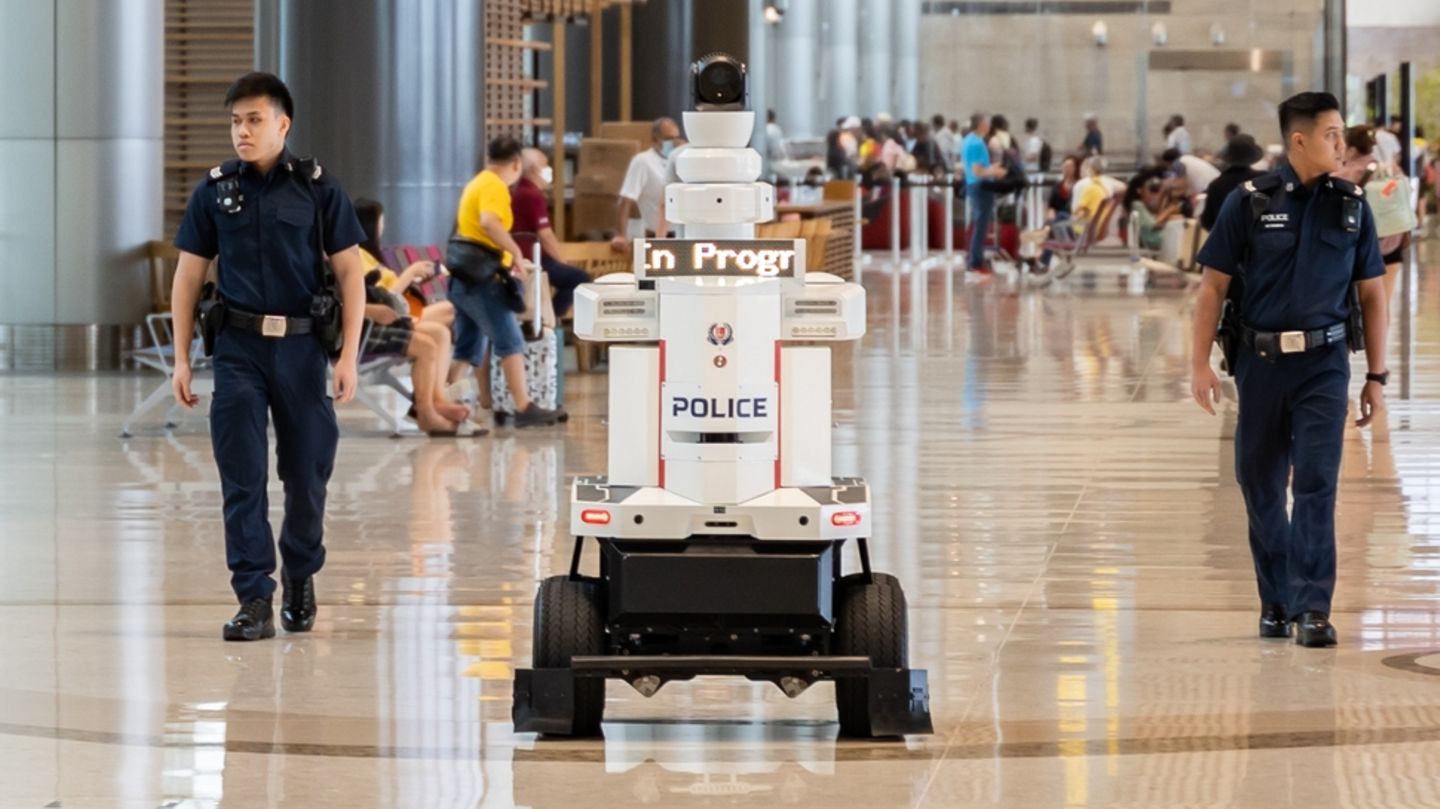 Polizisten patrouillieren an Seite des Roboters am Flughafen von Singapur