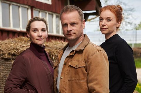 Drei Schauspieler:innen posieren vor einer Scheune
