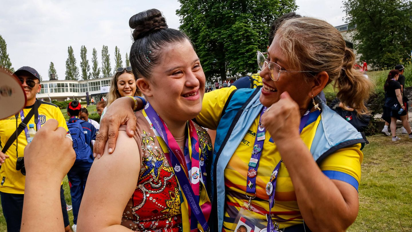 Eine Athletin freut sich mit einer Betreuerin über eine Medaille in Rhythmischer Sportgymnastik