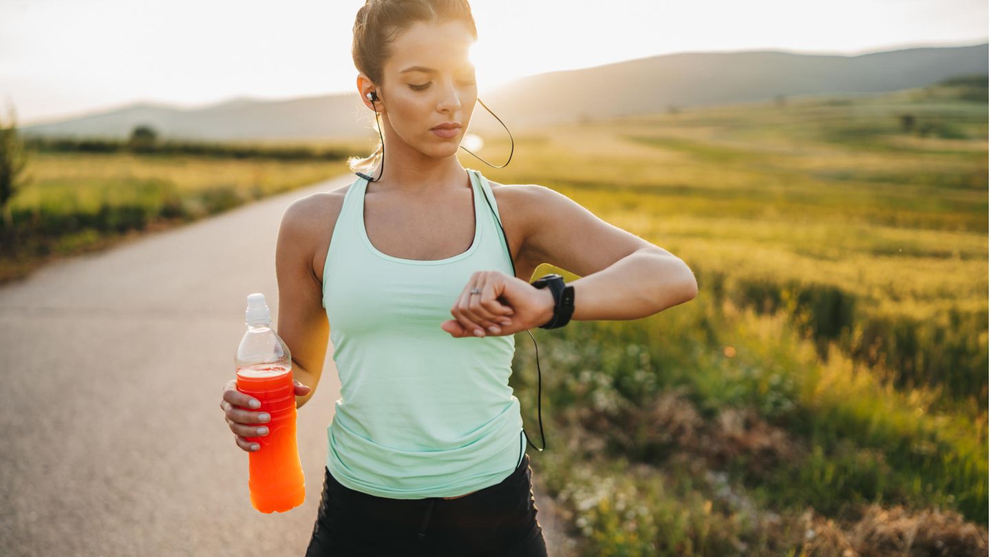 Eine Frau betreibt Sport und wertet Fitness-Daten per Smartwatch aus