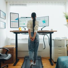 Laufband Schreibtisch: Eine Frau läuft auf einem Laufband unter ihrem Schreibtisch