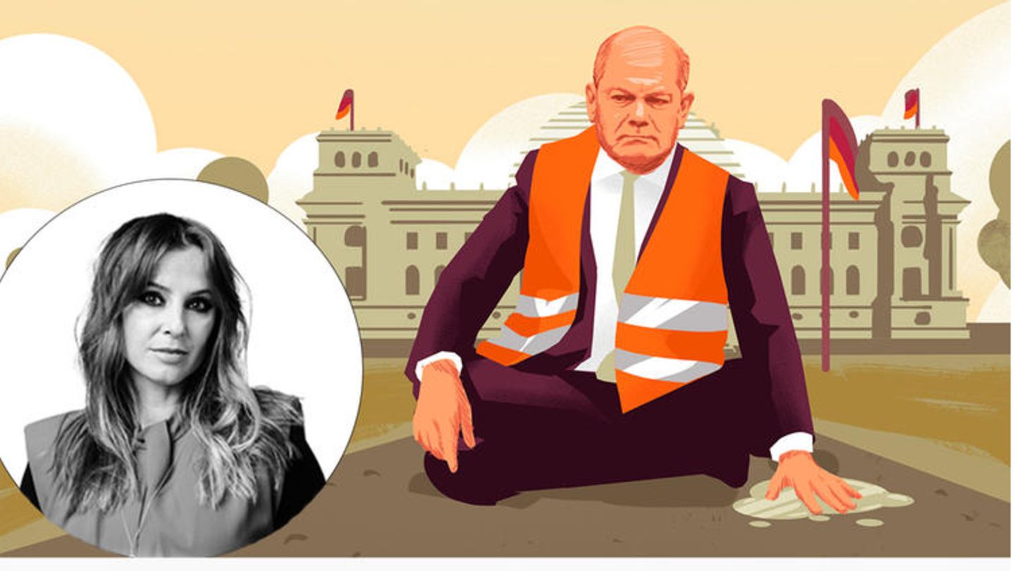 Olaf Scholz sitzt mit einer Warnweste vor dem Regierungsgebäude seine Hand klebt auf dem Boden