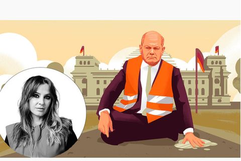 Olaf Scholz sitzt mit einer Warnweste vor dem Regierungsgebäude seine Hand klebt auf dem Boden