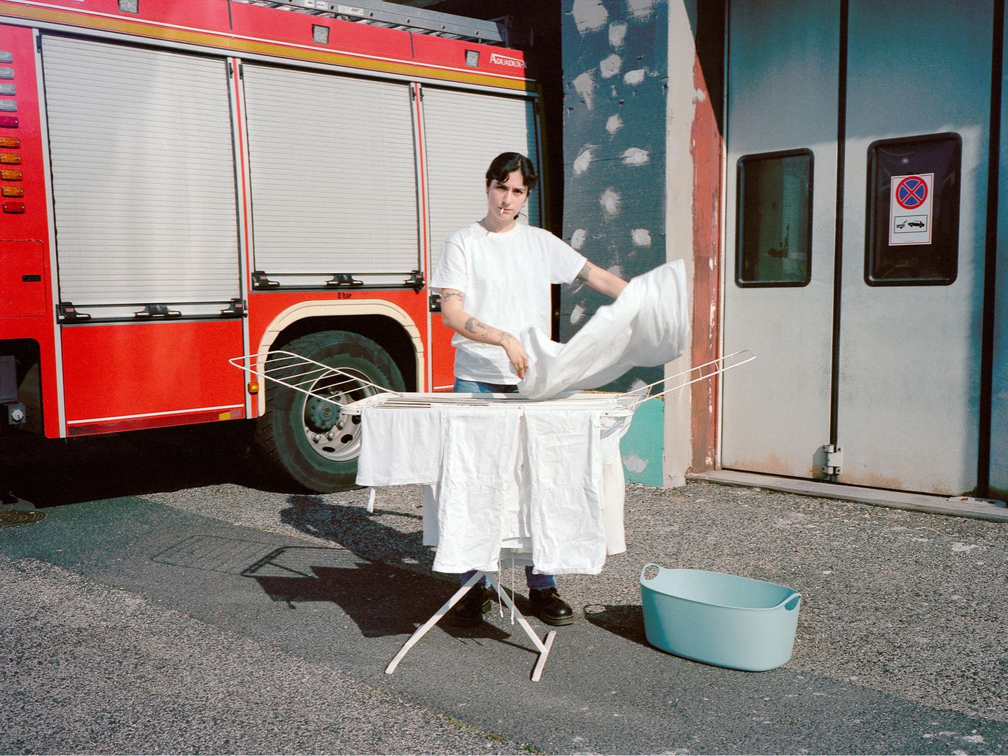 Asli Özçelic hangs laundry in front of a fire station