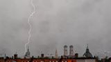 Ein Gewitter mit Blitzen zieht in den Abendstunden über die Dächer der bayerischen Landeshauptstadt.