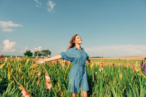 Outdoor-Porträt von hübschen jungen Mädchen in der Landschaft, trägt Jeanskleid, Arme weit offen