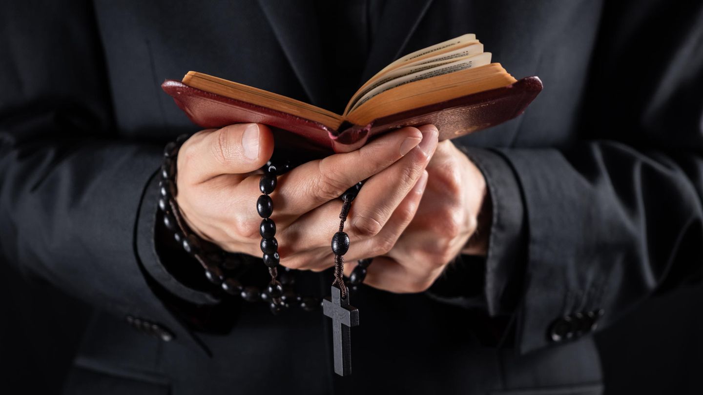 Priester mit Bibel und Kreuz