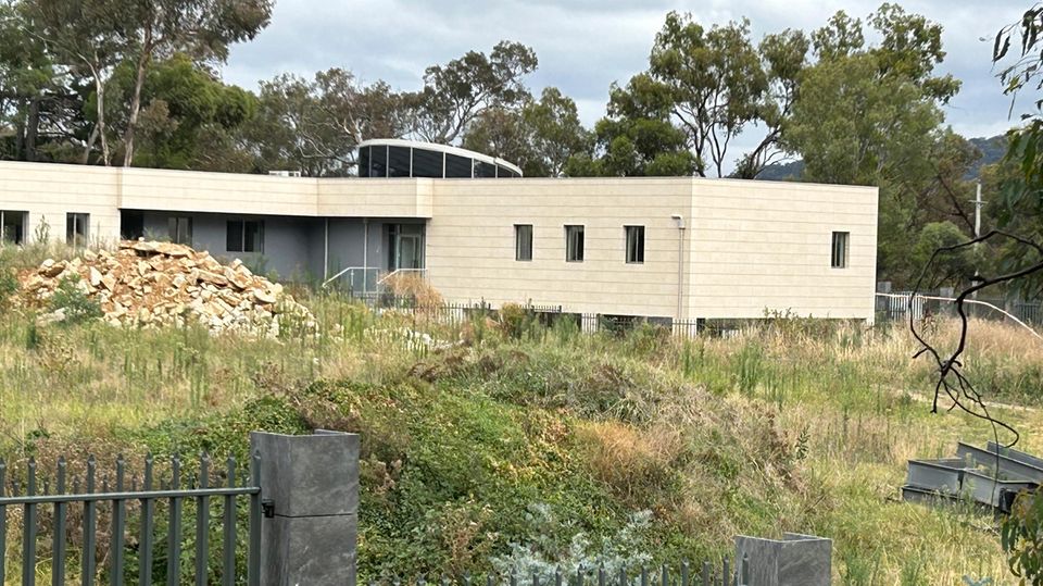 Ein Zaun umgibt ein scheinbar unbewohntes Gebäude auf dem Gelände einer geplanten neuen russischen Botschaft in Australien