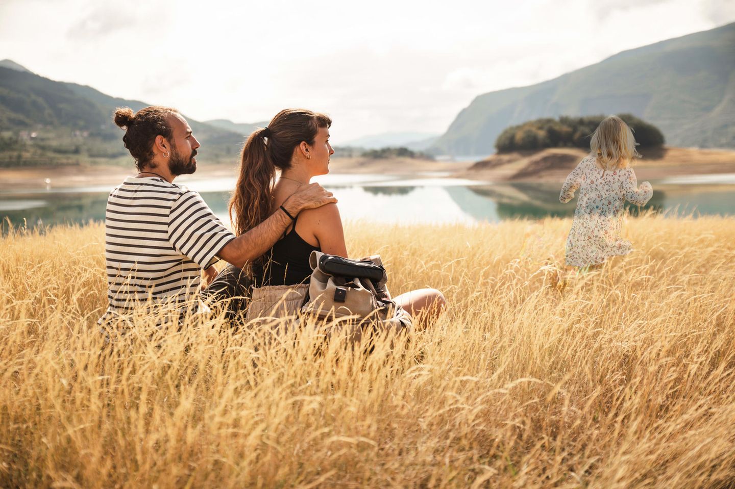 Kinderlos Glücklich Ein Paar sitzt auf einer Wiese. Ein Kind rennt davon.
