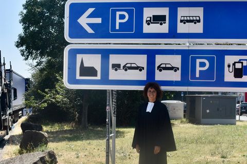 Pfarrerin Bea Ackermann vor dem Schild, das auf die Autobahnkirche hinweist