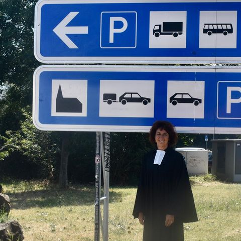 Pfarrerin Bea Ackermann vor dem Schild, das auf die Autobahnkirche hinweist
