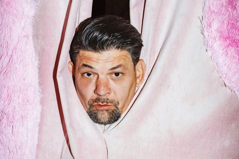 Der Kopf von Tim Mälzer blickt durch einen pinken Vorhang