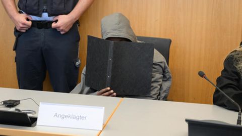 Prozess zum tödlichen Angriff in Illerkirchberg: Ein Mann mit Kapuze hält einen Ordner vor sein Gesicht