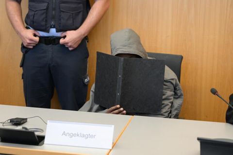 Prozess zum tödlichen Angriff in Illerkirchberg: Ein Mann mit Kapuze hält einen Ordner vor sein Gesicht