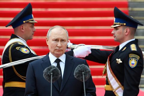 Putin steht vor einem Mikrofon, hinter ihm zwei Soldaten