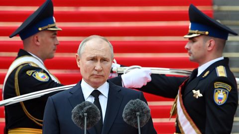 Putin steht vor einem Mikrofon, hinter ihm zwei Soldaten