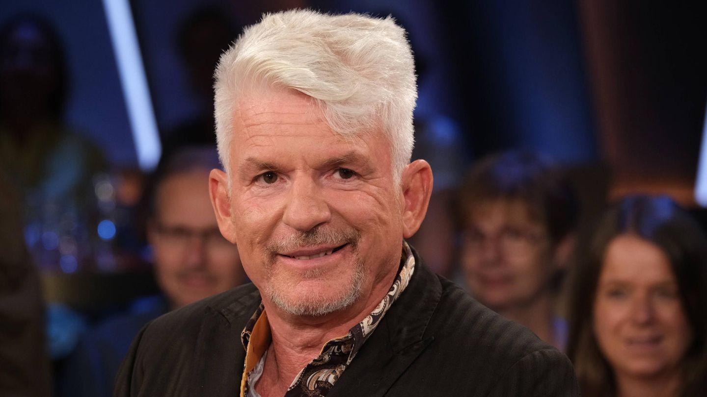 Heinz Strunk, ein Mann mit Tolle, lächelt in die Kamera