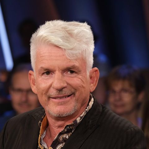 Heinz Strunk, ein Mann mit Tolle, lächelt in die Kamera