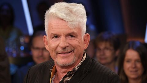 Heinz Strunk, ein Mann mit Tolle, lächelt in die Kamera