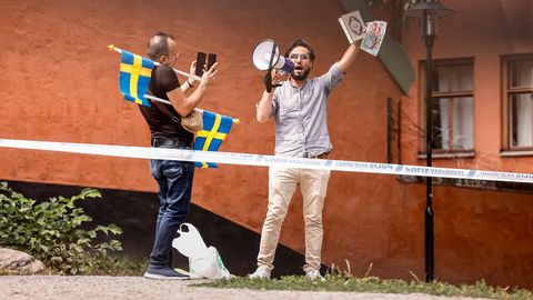 Ein nach Schweden geflüchtete Iraker hält den Koran hoch, ein weiterer Mann mit Schweden-Flaggen fotografiert ihn
