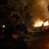 Ein Polizist steht während eines Zusammenstoßes mit Jugendlichen in Nanterre, außerhalb von Paris, an brennenden Autos