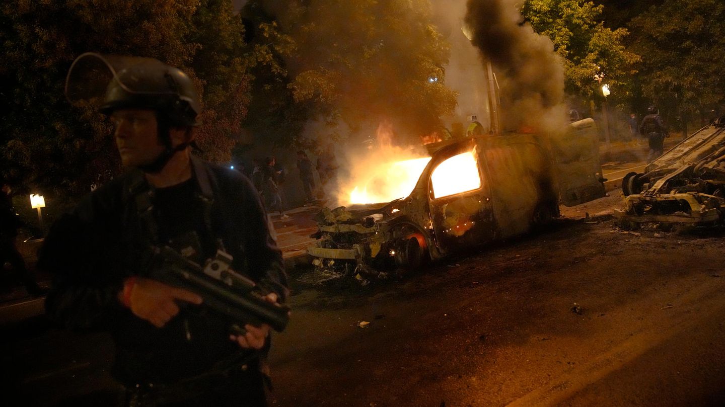 Ein Polizist steht während eines Zusammenstoßes mit Jugendlichen in Nanterre, außerhalb von Paris, an brennenden Autos
