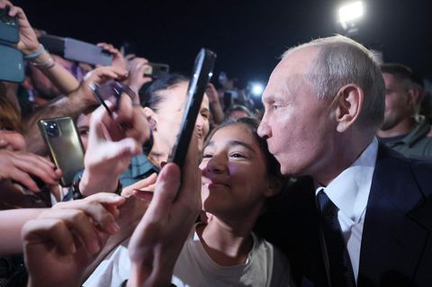 Wladimir Putin küsst beim Bad in der Menge in Derbent, Dagestan, eine junge Frau auf die Schläfe