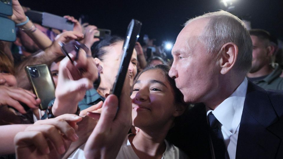 Wladimir Putin küsst beim Bad in der Menge in Derbent, Dagestan, eine junge Frau auf die Schläfe