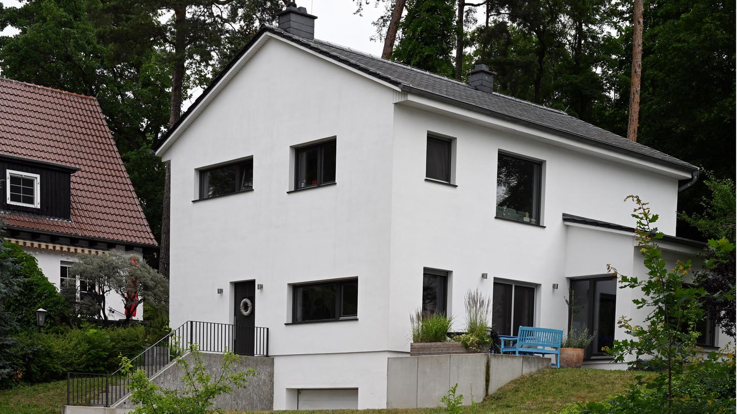 Ein weißes Haus mit asymmetrischen Fenstern steht auf einem Hanggrundstück vor einem Wald in Brandenburg