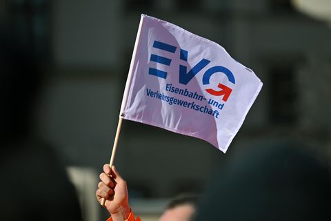 Eine Hand hält eine Flagge der Bahn-Gewerkschaft EVG in die Luft
