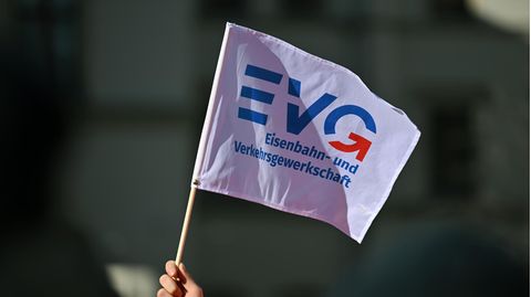 Eine Hand hält eine Flagge der Bahn-Gewerkschaft EVG in die Luft