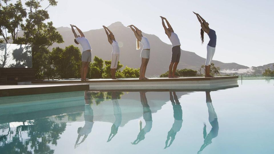 Eine Gruppe praktiziert Yoga am Pool