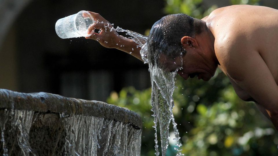 Ein Mann kühlt sich während der Hitzewelle in Mexiko mit Wasser aus einem Brunnen ab