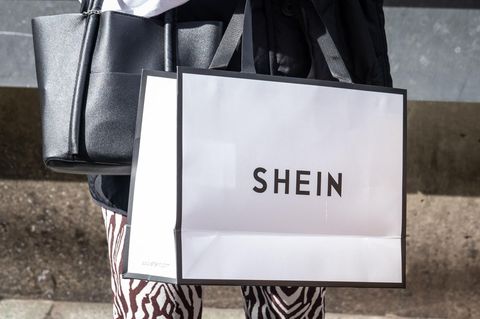 Eine Person trägt eine Shoppingtüte des Modekonzerns Shein