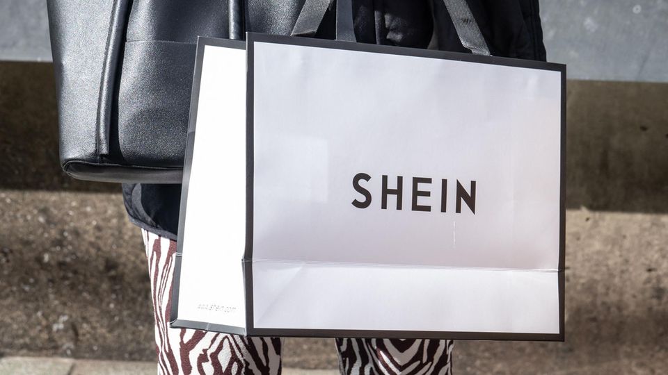 Eine Person trägt eine Shoppingtüte des Modekonzerns Shein