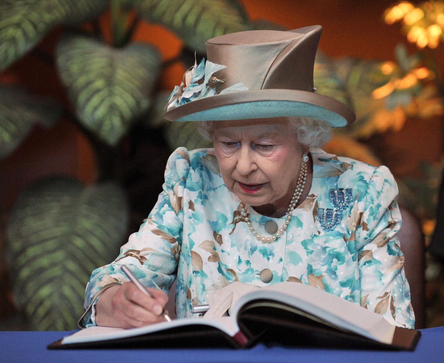 Queen Elisabeth II. schreibt in ein Gästebuch