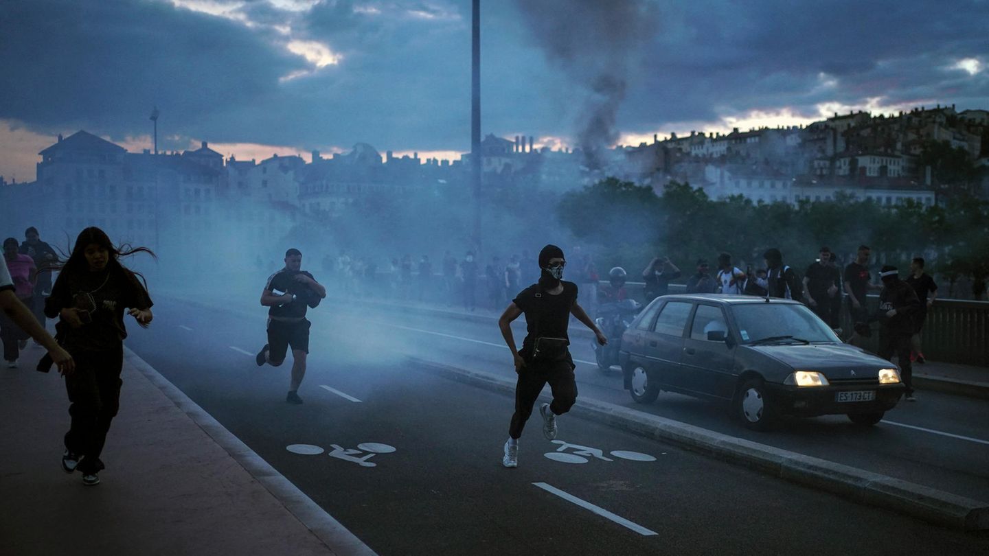 Menschen fliehen auf der Straße in Lyon, während es zu einem Zusammenstoß mit der Polizei kommt.