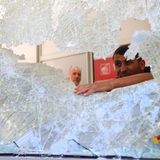 Zwei Männer untersuchen ein zerbrochenes Ladenfenster in der Stadt Marseille.