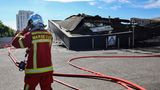 Ein Feuerwehrmann steht in Marseille vor einem ausgebrannten Supermarkt.