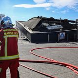 Ein Feuerwehrmann steht in Marseille vor einem ausgebrannten Supermarkt.