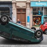 Ein Polizeibeamter inspiziert ein Auto, das in Lyon von Protestierenden auf den Kopf gestellt wurde.