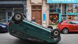 Ein Polizeibeamter inspiziert ein Auto, das in Lyon von Protestierenden auf den Kopf gestellt wurde.
