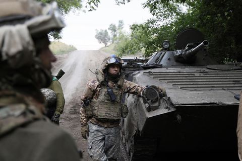 Ukrainische Soldaten neben einem gepanzerten Transporter.